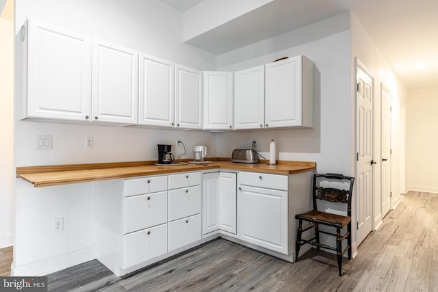 kitchen featuring light wood-type flooring, butcher block countertops, baseboards, and white cabinets