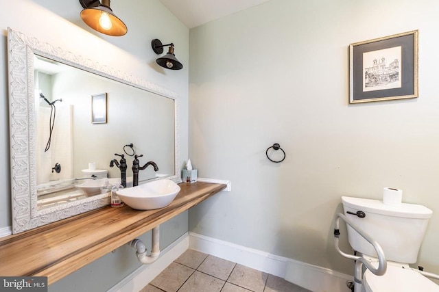 bathroom featuring toilet, tile patterned flooring, baseboards, and a sink