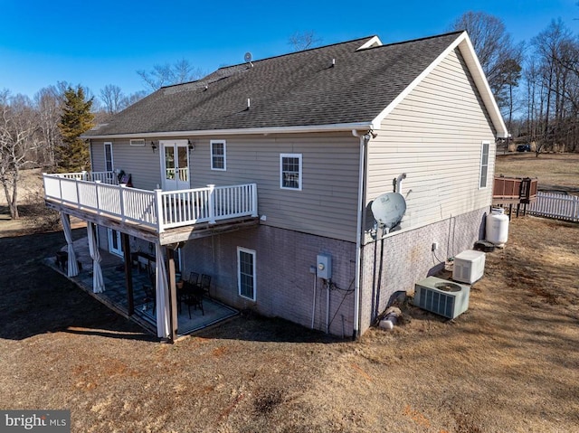 rear view of property with french doors, roof with shingles, cooling unit, and a wooden deck