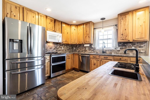 kitchen with hanging light fixtures, appliances with stainless steel finishes, a sink, and decorative backsplash