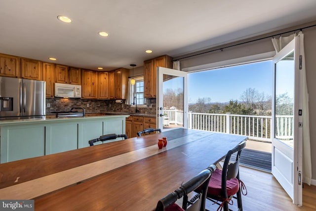 kitchen featuring brown cabinets, decorative light fixtures, dark countertops, stove, and white microwave