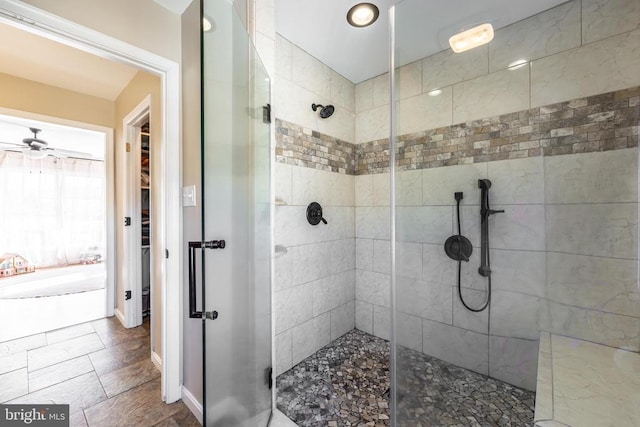 full bath with ceiling fan, a stall shower, and baseboards