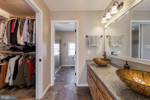 full bath featuring a sink, double vanity, a walk in closet, and a shower stall