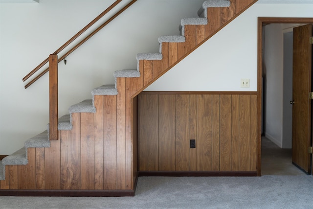 stairway with carpet floors and wood walls