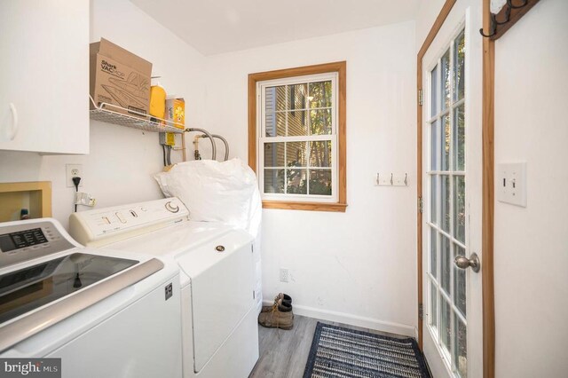 laundry area featuring washer and clothes dryer, wood finished floors, cabinet space, and baseboards