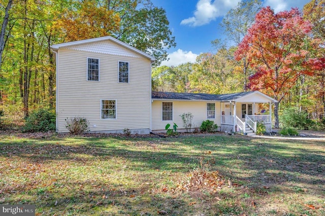 view of front of home featuring a porch, a front yard, and a forest view