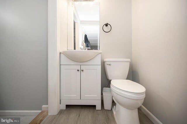 bathroom with toilet, baseboards, wood finished floors, and vanity