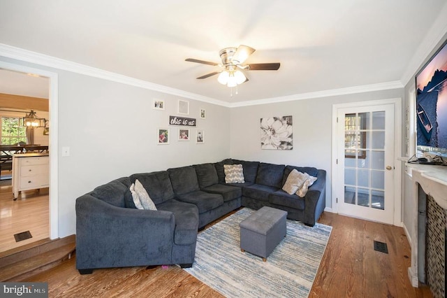 living room with wood-type flooring, ornamental molding, and ceiling fan