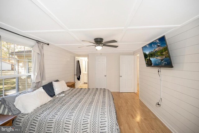 bedroom with coffered ceiling, light hardwood / wood-style flooring, ceiling fan, and wood walls