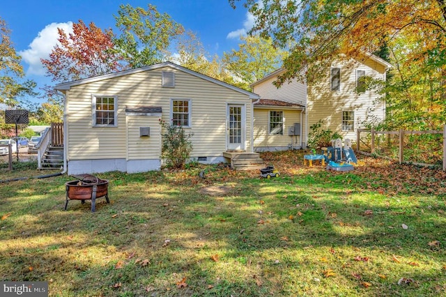 back of house featuring an outdoor fire pit and a yard