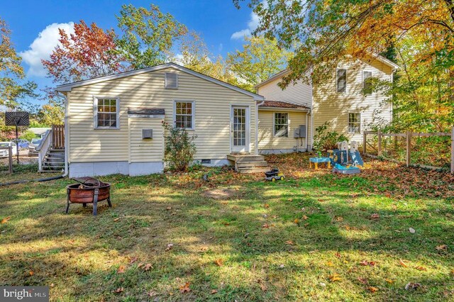 back of house with a fire pit, crawl space, a lawn, and fence