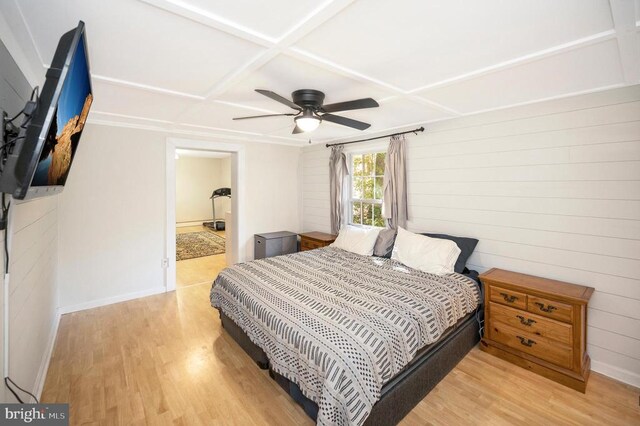 bedroom featuring coffered ceiling, wood walls, ceiling fan, and light hardwood / wood-style flooring