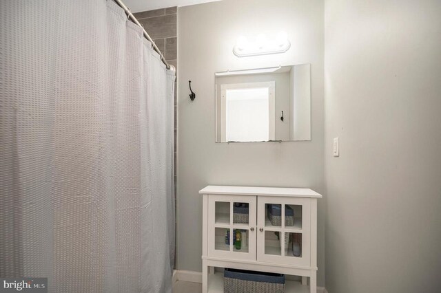 full bathroom featuring a shower with shower curtain and baseboards