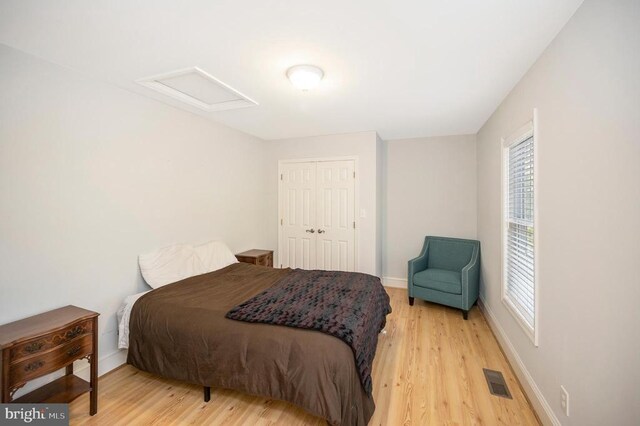 bedroom featuring a closet, light hardwood / wood-style floors, and multiple windows