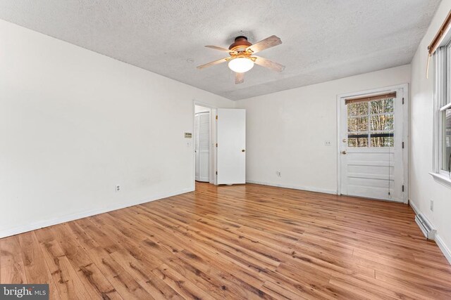 empty room with ceiling fan, light hardwood / wood-style flooring, and a textured ceiling