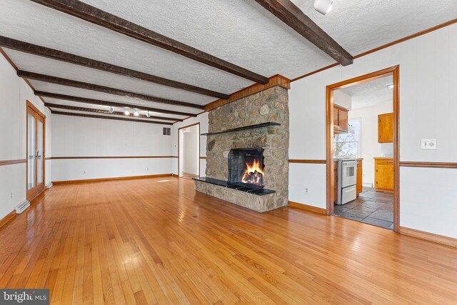 unfurnished living room featuring beam ceiling, hardwood / wood-style flooring, a fireplace, and a textured ceiling