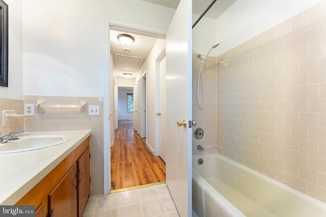 bathroom featuring tile walls, tile patterned flooring, vanity, tiled shower / bath combo, and a textured ceiling