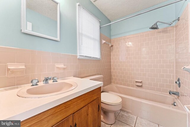 full bathroom featuring tile patterned flooring, vanity, a textured ceiling, toilet, and tiled shower / bath