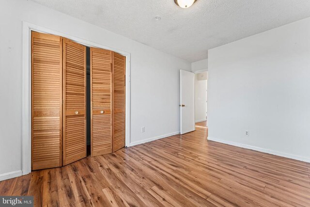 unfurnished bedroom with light hardwood / wood-style floors, a closet, and a textured ceiling