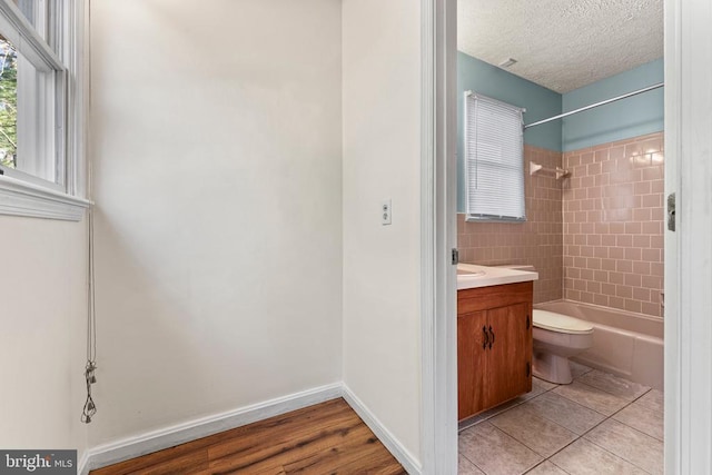 full bathroom with tile patterned floors, toilet, tiled shower / bath, a textured ceiling, and vanity