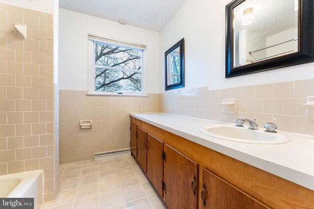 bathroom featuring vanity, tile patterned flooring, a textured ceiling, and tile walls