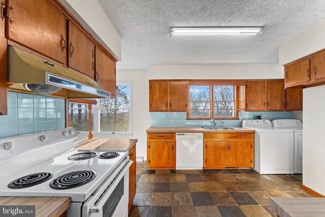 kitchen with independent washer and dryer, white appliances, a healthy amount of sunlight, and sink