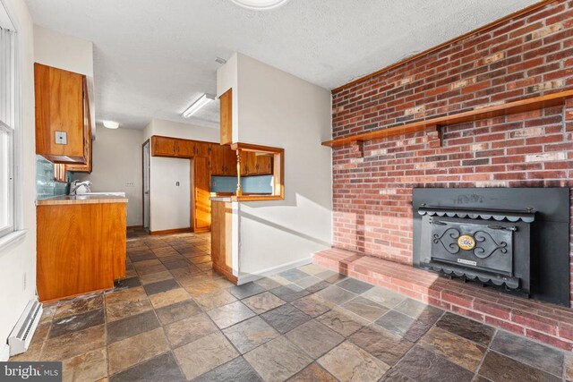 kitchen with a baseboard heating unit, sink, and a textured ceiling