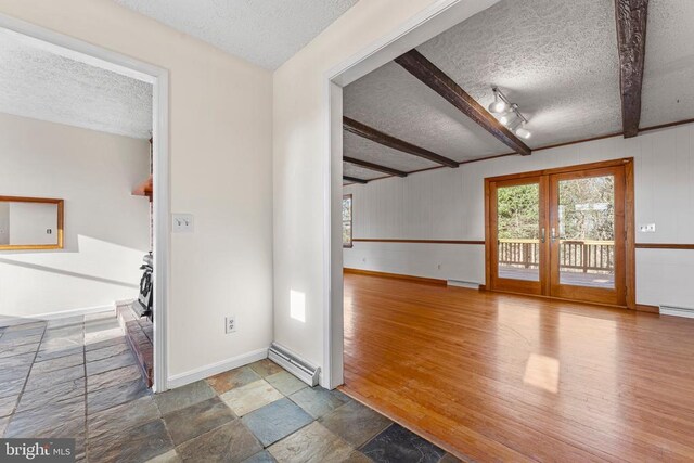 foyer entrance with hardwood / wood-style flooring, beamed ceiling, french doors, and a textured ceiling