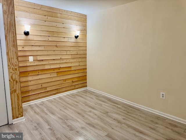 empty room featuring light hardwood / wood-style floors and wood walls