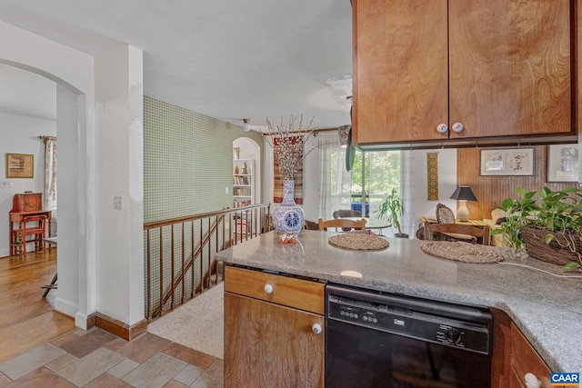 kitchen with arched walkways, baseboards, black dishwasher, and brown cabinets