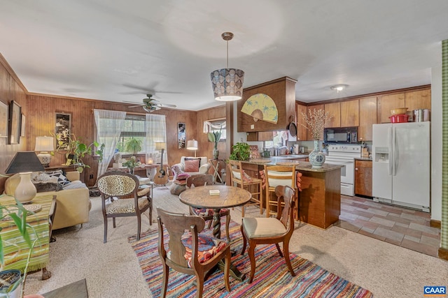 dining space featuring wood walls and ceiling fan
