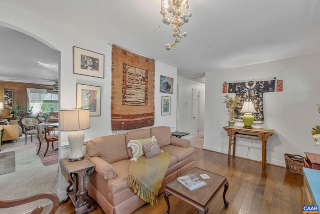 living area featuring an inviting chandelier, arched walkways, baseboards, and wood-type flooring