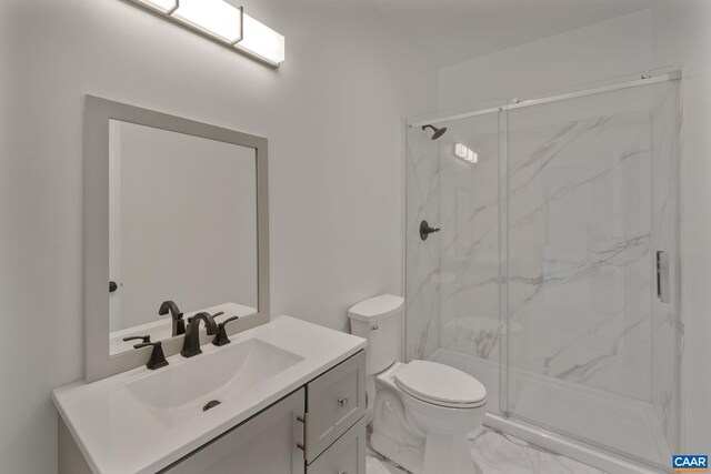 bathroom featuring vanity, a shower with shower door, and toilet