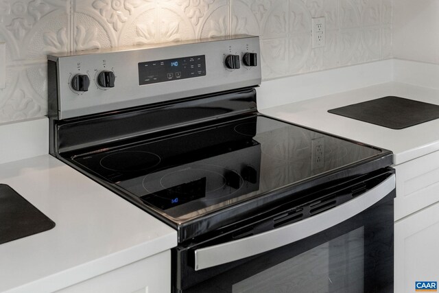 kitchen featuring stainless steel range with electric stovetop, white cabinetry, and tasteful backsplash