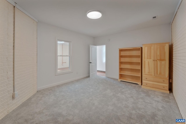 unfurnished bedroom featuring brick wall and carpet flooring