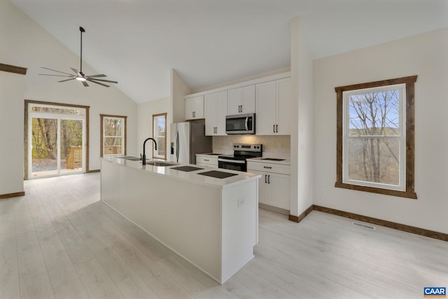 kitchen featuring a kitchen island with sink, white cabinetry, plenty of natural light, and stainless steel appliances