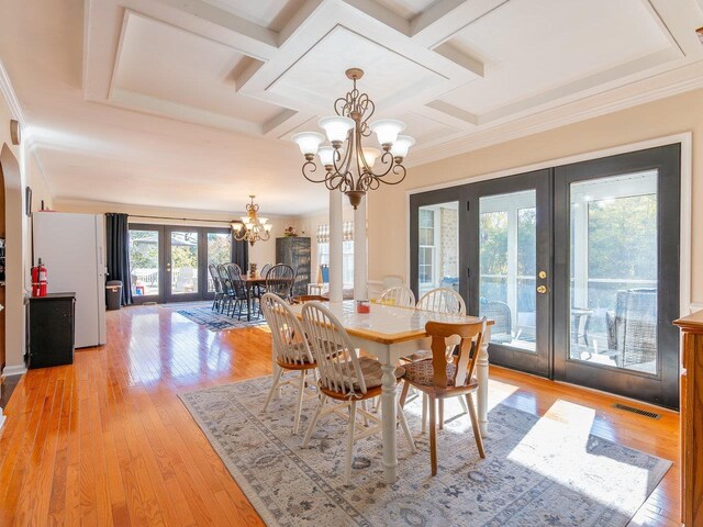 dining room featuring coffered ceiling, a notable chandelier, light hardwood / wood-style flooring, and french doors