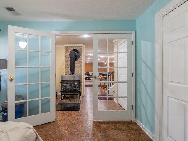 entryway with a wood stove, a textured ceiling, and french doors