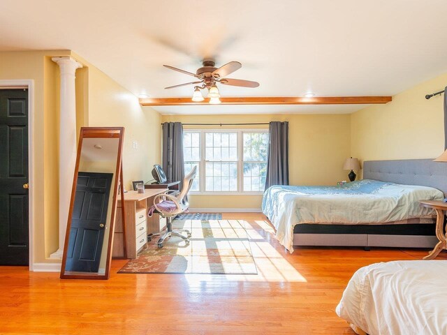 bedroom featuring ornate columns, ceiling fan, light wood-type flooring, and beamed ceiling