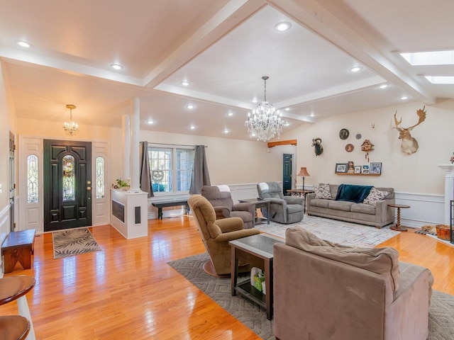 living room featuring vaulted ceiling with beams, light hardwood / wood-style flooring, and a notable chandelier