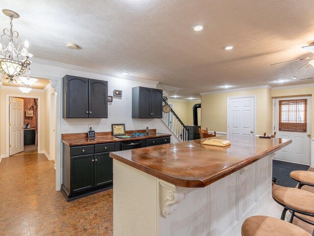 kitchen with hanging light fixtures, crown molding, a center island, and wooden counters