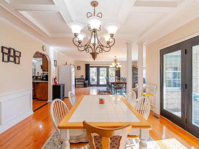 dining room with coffered ceiling, ornamental molding, light hardwood / wood-style floors, french doors, and a chandelier