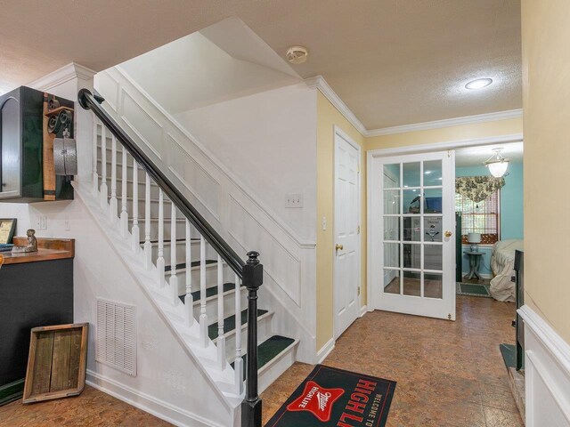 entrance foyer featuring ornamental molding and a textured ceiling