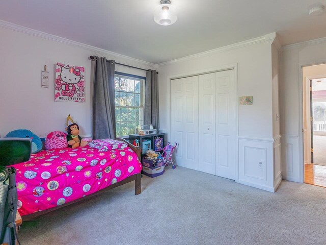 carpeted bedroom with ornamental molding and a closet