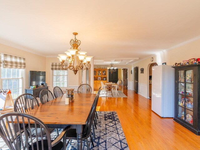 dining room with a notable chandelier, crown molding, and light hardwood / wood-style floors