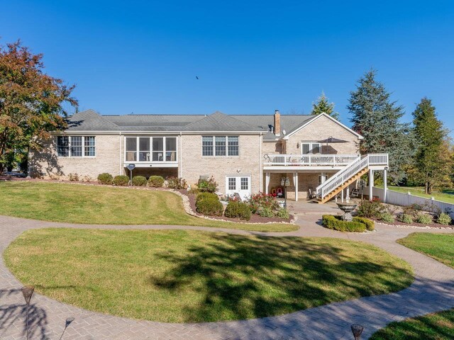 view of front of house featuring a wooden deck, a patio, and a front yard