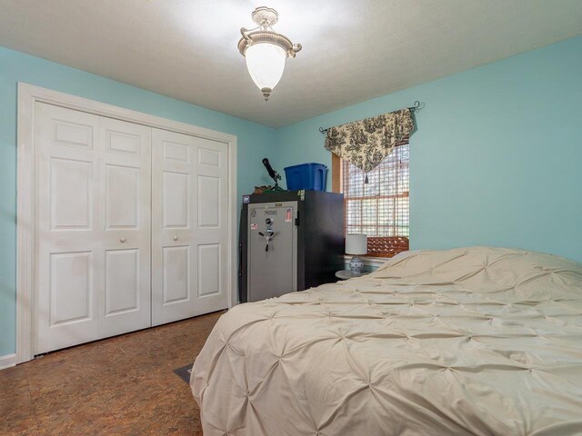 bedroom with stainless steel refrigerator and a closet