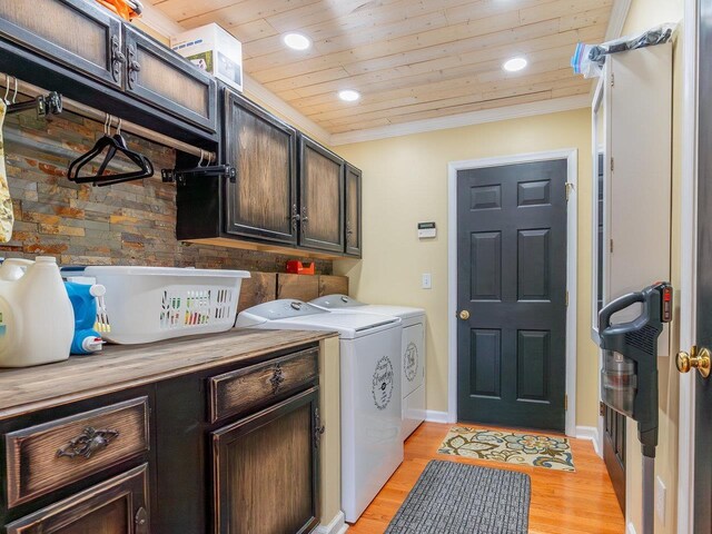 laundry area featuring cabinets, wooden ceiling, ornamental molding, washer and clothes dryer, and light hardwood / wood-style floors