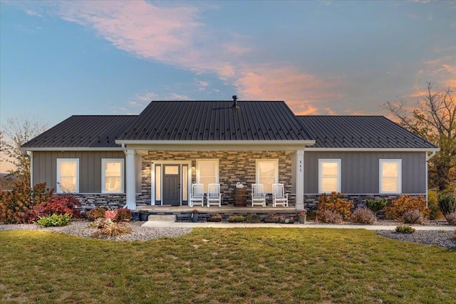 back house at dusk with a lawn and a porch