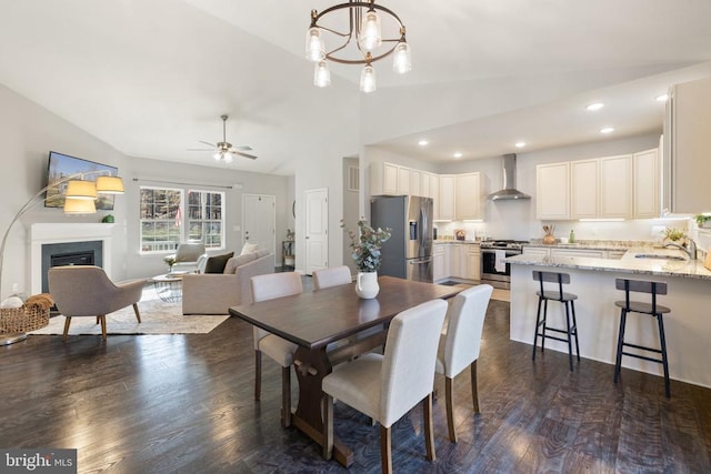 dining area with ceiling fan with notable chandelier, dark wood-style floors, recessed lighting, a fireplace, and lofted ceiling